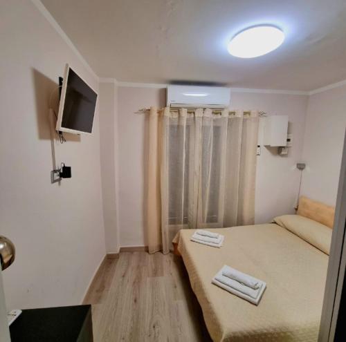 Habitación pequeña con cama y TV de pantalla plana. en Tiny Little Home - Casa Vacanze ad Uso Esclusivo, en Nápoles