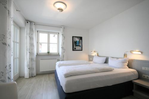 a white bedroom with a large bed and a window at Ferienwohnung Stephan in Füssen