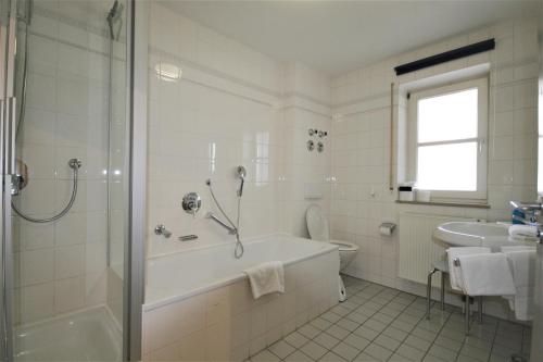 a white bathroom with a tub and a sink at Ferienwohnung Stephan in Füssen