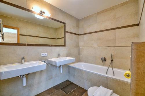 a bathroom with two sinks and a tub and a toilet at Alpin & Seeresort Penthouse 18 - by Alpen Apartments in Zell am See