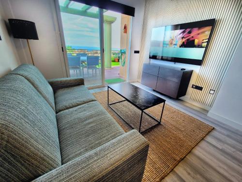 a living room with a couch and a flat screen tv at Alcaidesa, luxury apartment with sea views in Alcaidesa