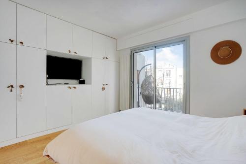 een witte slaapkamer met een bed en een raam bij Very nice apt in the heart of Neuilly with Parking in Neuilly-sur-Seine