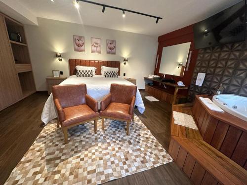 a bedroom with a bed and a tub and a bed and a chair at Pousada Princesa Isabel - Visconde in Petrópolis
