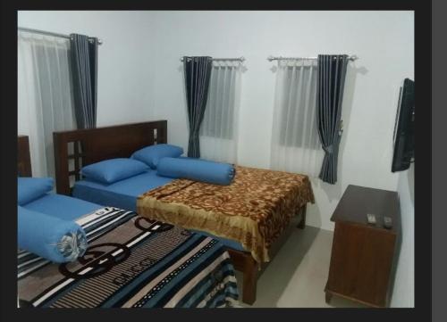 a bedroom with a bed with blue pillows at Kota Baru Homestay Jepara in Jepara