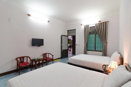 a hotel room with two beds and a tv at Thuy Loi Hotel in Hoi An