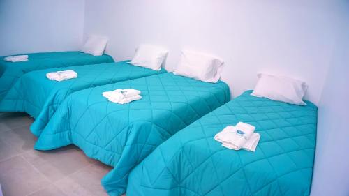 three beds in a room with green comforters at LAS GAVIOTAS DE PARACAS in Paracas