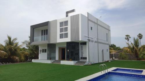 a large white house with a swimming pool in front of it at Coastal Heaven Koovathur in Kūvattūr