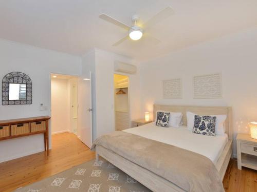 a white bedroom with a bed and a ceiling fan at Beach Villa - a Short Walk to Town & Beach in Port Douglas