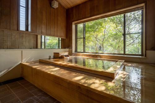 a bath tub in a room with a large window at Jinya Ryokan in Hadano