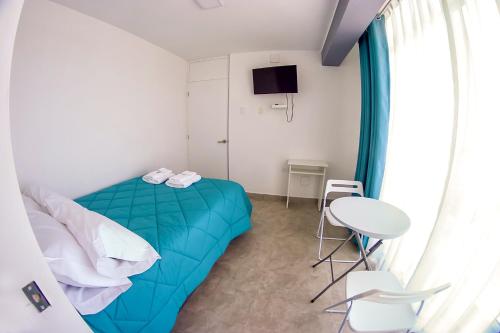 1 dormitorio con 1 cama azul, mesa y sillas en LAS GAVIOTAS DE PARACAS, en Paracas
