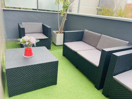 a patio with two chairs and a table with a vase of flowers at Luxe Forum Beach Terrace in Sant Adria de Besos