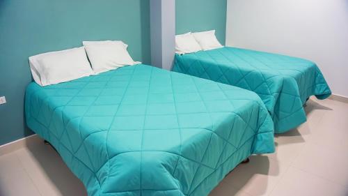 two beds with blue sheets in a room at LAS GAVIOTAS DE PARACAS in Paracas