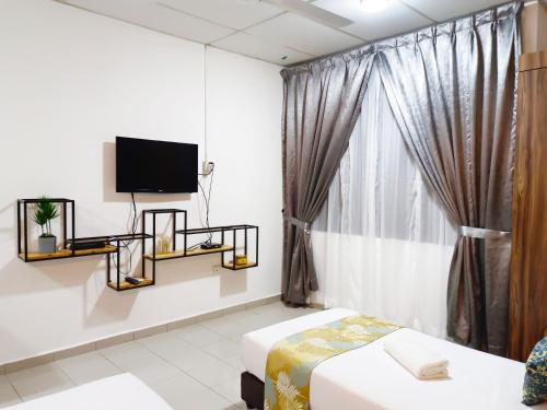 a room with a bed and a tv and a window at Salaam Suites Hotel in Kota Bharu