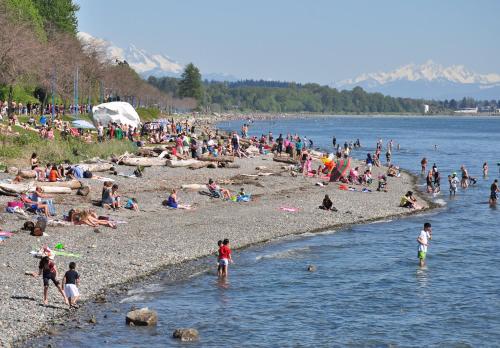 a crowd of people on a beach near the water at JESI'S NEW HOUSE, Self Enter 2BR, Whole Suite, Close to White Rock Beach & US Border in Surrey