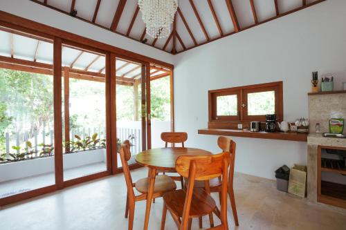 uma sala de jantar com mesa, cadeiras e janelas em Karyana Apartment em Kuta Lombok