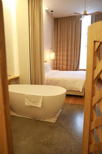 ein Badezimmer mit einer Badewanne und ein Schlafzimmer mit einem Bett in der Unterkunft Shanghai Pudong Airport Moonlo Hotel - Pet Friendly in Shanghai