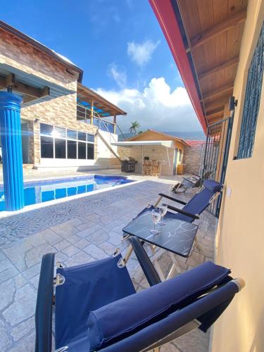a patio with chairs and a table and a pool at Villa Bellevue in San Felipe de Puerto Plata