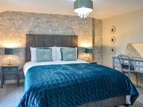 a bedroom with a large bed with a blue blanket at Heather Cottage in Bishop Auckland