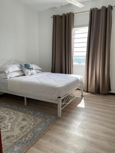 ein Schlafzimmer mit einem Bett und einem Fenster mit Vorhängen in der Unterkunft Aida Homestay in Kuala Terengganu