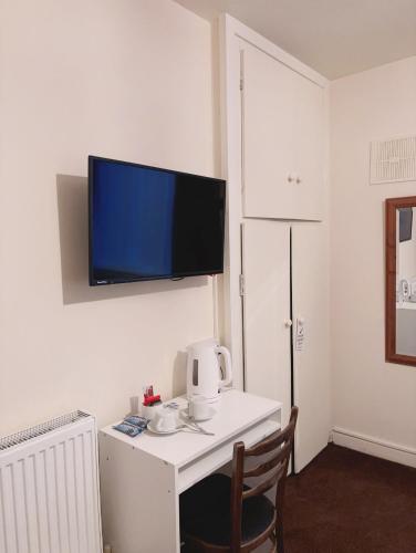 a room with a white desk with a tv on the wall at Mulgrave Lodge in Dun Laoghaire