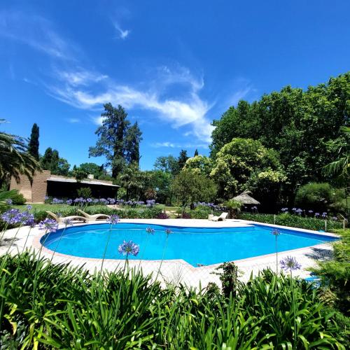 uma grande piscina num jardim com flores em Casa Principal - El Bamboo Eventos em Arturo SeguÃ­