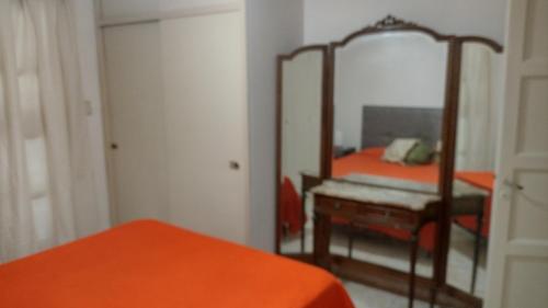 - une chambre avec un lit orange et un miroir dans l'établissement Como en casa, à Mendoza