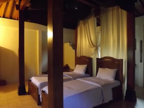 a bedroom with two beds in a room with yellow walls at Rumah Dharma in Borobudur