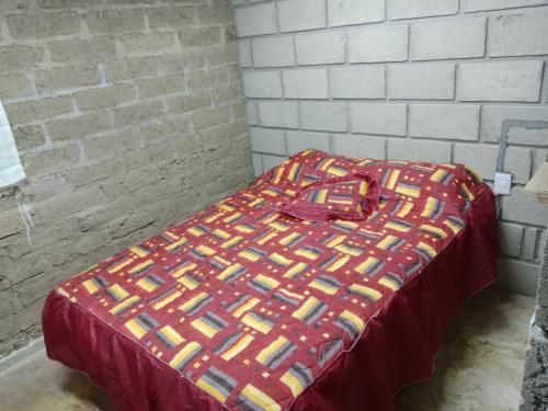 Una cama con una manta de colores encima. en Las escondidas, en Pueblo Nuevo