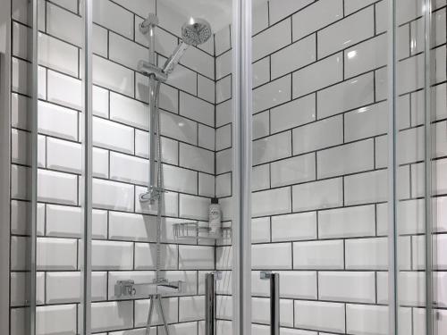 a bathroom with white tiled walls and a mirror at The Frome Studio in Frome