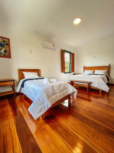 two beds in a large room with wooden floors at Pousada do Gentil in Tiradentes