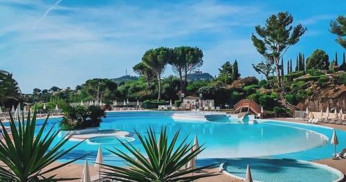 une grande piscine avec de l'eau bleue et des arbres dans l'établissement Cap Estérel T3 jardin clôturé Grande terrasse couverte Vue Mer 2 chambres Village vacances Pierre et vacances, à Saint-Raphaël