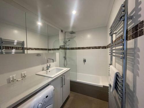 a white bathroom with a sink and a bath tub at Lawlers 42 in Mount Hotham