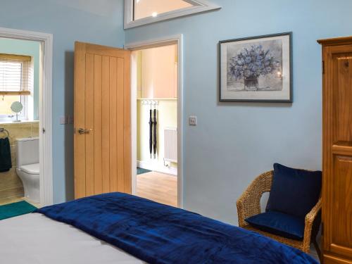 a bedroom with a blue bed and a chair at The Squirrels in Great Malvern