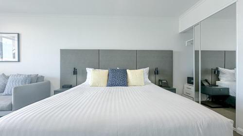 a bedroom with a large white bed with blue pillows at Oaks Toowoomba Hotel in Toowoomba