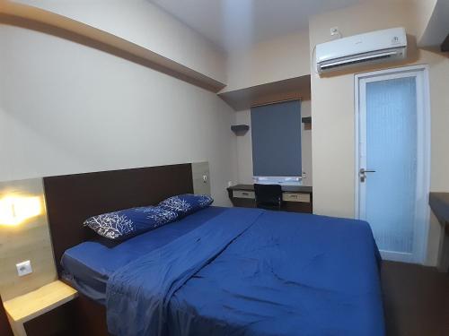 sypialnia z niebieskim łóżkiem i oknem w obiekcie Tamansari Mahogany Apartment By Sagita Residence Karawang w mieście Karawang
