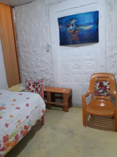 a bedroom with a bed and a chair and a table at CABAÑA MISSRAÍ TROPICAL in Loma del Naranjo