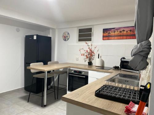 eine Küche mit einem schwarzen Kühlschrank und einem Tisch in der Unterkunft L Oasis des kassaveries in Capesterre-Belle-Eau