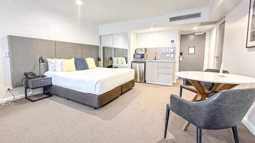 a bedroom with a bed and a table and chairs at Oaks Toowoomba Hotel in Toowoomba