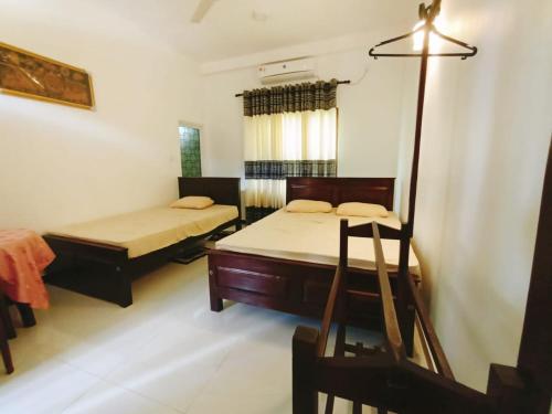Habitación con 2 camas y lámpara. en Hotel Sanhida Polonnaruwa, en Polonnaruwa