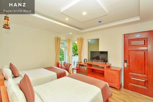 a hotel room with two beds and a television at HANZ HOPAPA Hotel Phu Quoc in Phu Quoc