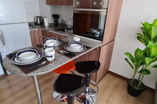 una cocina con una mesa con platos. en Moderno Departamento, en Santiago