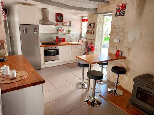 - une cuisine avec une table et des tabourets dans l'établissement Gîte cosy avec spa, jardin et équipement complet à Bourgueil, près des Châteaux de la Loire - FR-1-381-564, à Bourgueil