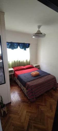 een slaapkamer met een bed met een rode deken en een raam bij Centro de Rosario Departamento de 1 habitación in Rosario