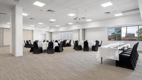 a conference room with white tables and black chairs at Oaks Toowoomba Hotel in Toowoomba