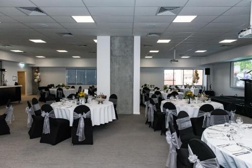 a banquet hall with white tables and black chairs at Oaks Toowoomba Hotel in Toowoomba