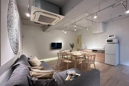 a living room with a couch and a kitchen with a table at bHOTEL Art Bldg - Modern 2BR City Center for 8ppl in Ōsukachō