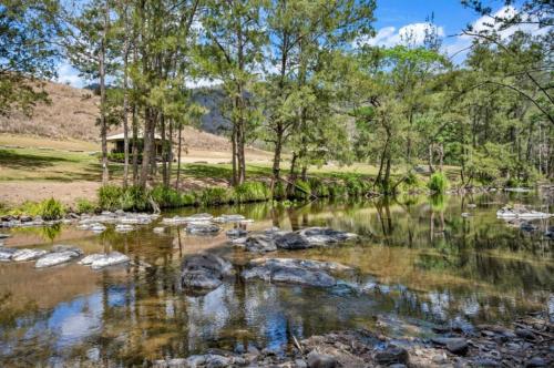 a creek with rocks and trees in the background at Amaroo Escape in Coneac