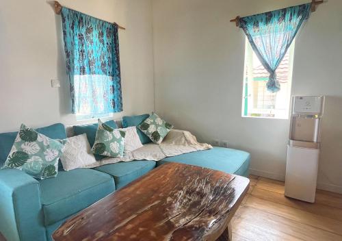 ein Wohnzimmer mit einem blauen Sofa und einem Tisch in der Unterkunft Mentawai Katiet Beach House, Lance's Right HTS in Katiet