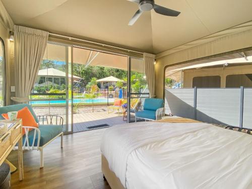 a bedroom with a bed and chairs and a patio at Magnetic Glamping Tent 10 in Nelly Bay