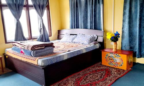 a bedroom with a bed with blue curtains and a window at Zen homestay in Ravangla